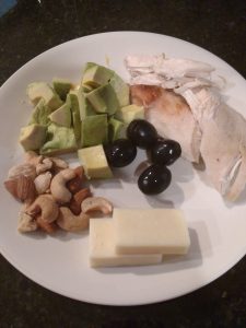 cubed avocado, chicken, black olives, block cheese and mixed nuts on plate.