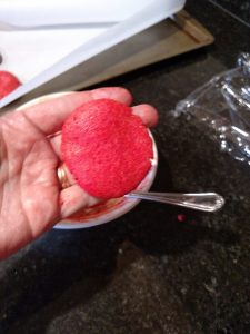 red dough formed into shape of cookie in hand.