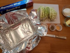 foil lined baking pan, chopped cabbage and other ingredients ready to make baked cabbage and onions