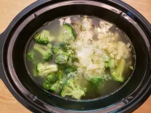 broccoli and cauliflower in broth in crock pot before cooking