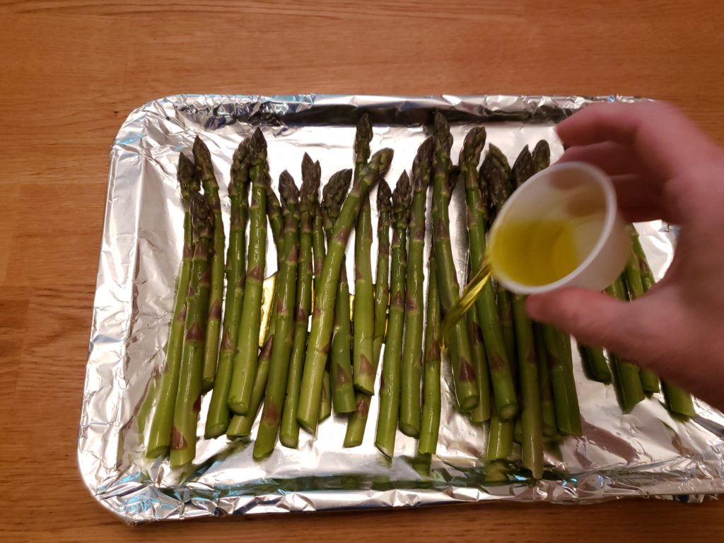 drizzling olive oil over asparagus