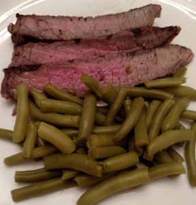 Grilled Marinated London Broil and green beans on white plate
