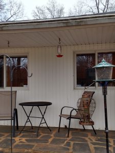 a hummingbird feeder hanging from a porch roof.