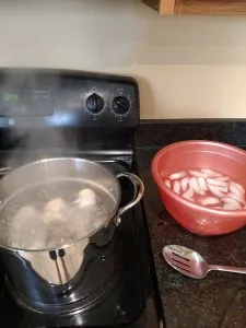 eggs boiling on stove and bowl of ice water next to them