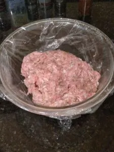 sausage in bowl covered in plastic wrap