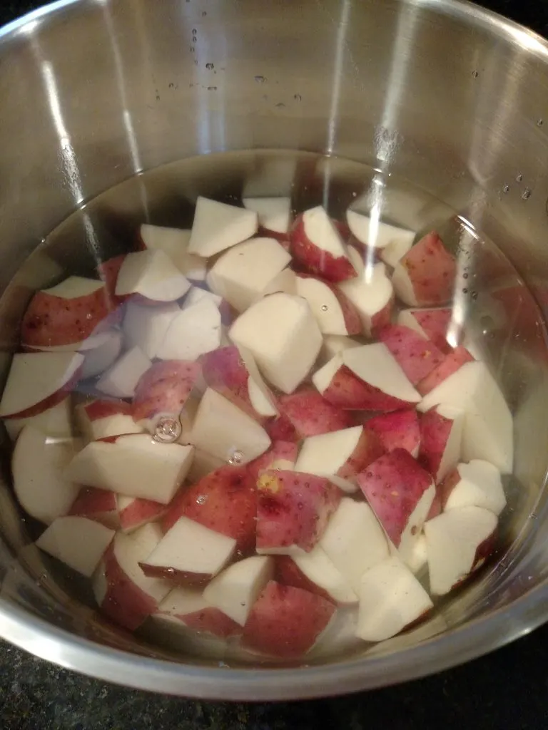red potatoes in water in saucepan on stove