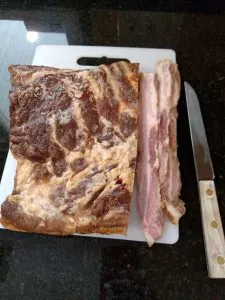 bacon on cutting board with few slices cut