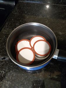 small pan with water and canner lids on the stove.