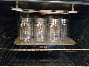 canning jars on a baking sheet in oven.