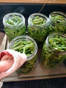 wiping the mouth of canning jar with dish towel so it is clean.