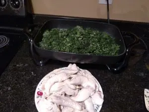 chicken on plate after starting to cook and spinach cooking in skillet