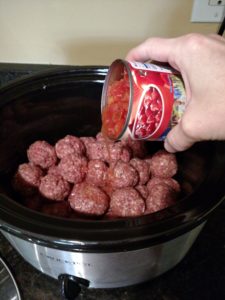 pouring tomatoes over Low Carb Crock Pot Meatballs in crock pot