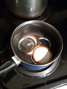 lids to canning jars in small pan of water to heat them.