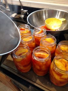 adding syrup to jars of peaches.