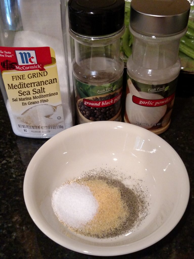 salt, pepper and garlic powder in bowl and bottles behind it