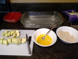 sliced eggplant on left, bowl with egg in middle, bowl with breading on right