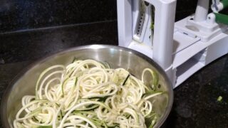 zoodles in bowl next to spiralizer