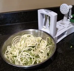 zoodles in bowl next to spiralizer