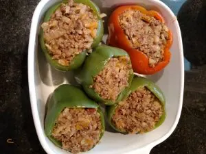 4 peppers in baking dish with meat and cauliflower filling in them