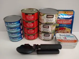 4 cans tuna, 4 cans salmon, 3 cans chicken breast, 2 foil packs salmon, 2 cans sardines, manual can opener in front.