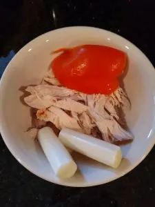 orange pepper quarter, rotisserie chicken and string cheese in bowl.