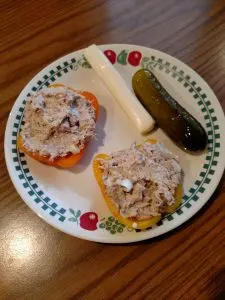 tuna salad on two bell pepper halves, string cheese and pickle on plate. 