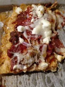 rectangle piece of pizza topped with meats and cheese.