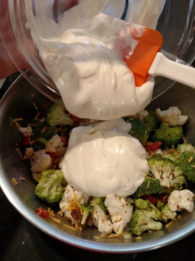 pouring dressing over vegetables and bacon in bowl