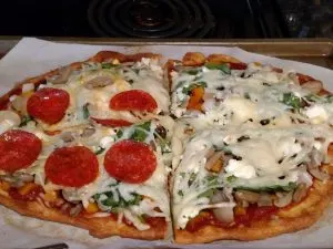 pizza cut in quarters and topped with pepperoni, lots of veggies and cheese.