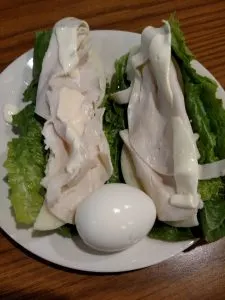 romaine lettuce leaves, cheese and turkey lunchmeat to roll into a sandwich wrap and hard boiled egg on a plate