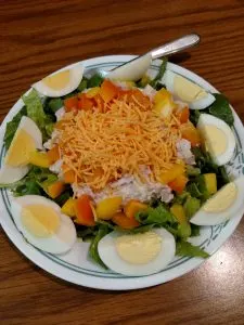 salad with hard boiled egg quarters around the edges and shredded cheese on top