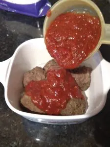 pouring sauce over meatballs.