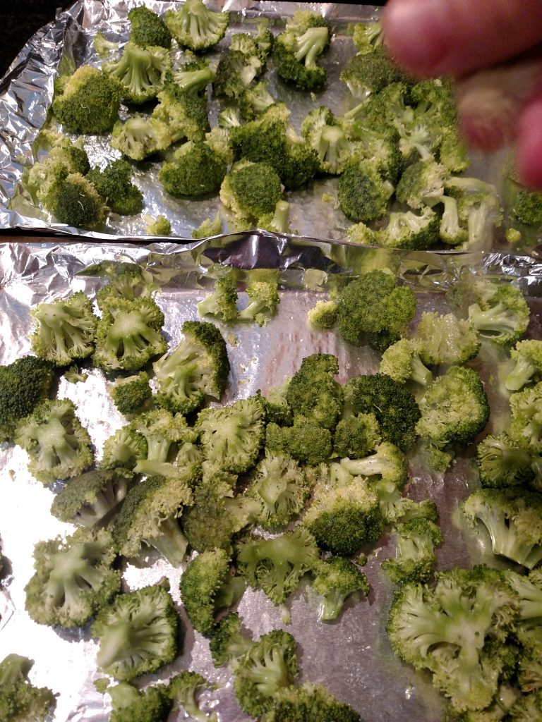 sprinkling seasoning on Broccoli