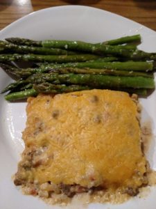 Keto Cheesy Taco Beef Casserole on a plate with asparagus