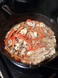 cooking mushrooms, peppers and onions in skillet