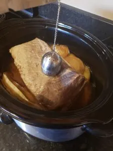 showing pulling tea bag out of crock pot of corned beef and cabbage