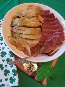 corned beef and cabbage sliced on white plate on green tablecloth