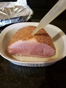 basting ham in white baking dish