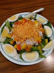 salad with shredded cheese on top and hard boiled egg quarters around the edge