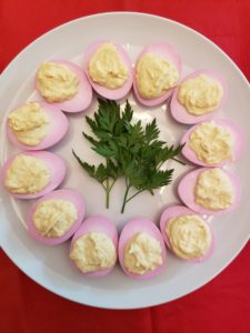 Deviled Red Beet Eggs on white plate with parsley sprigs in the center