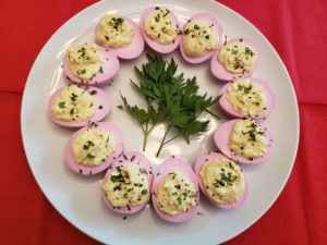 Deviled Red Beet Eggs on white plate with parsley sprigs in the center