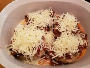chicken in baking dish with sauce and cheese on top