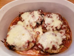 chicken in baking dish with sauce and cheese on top baked