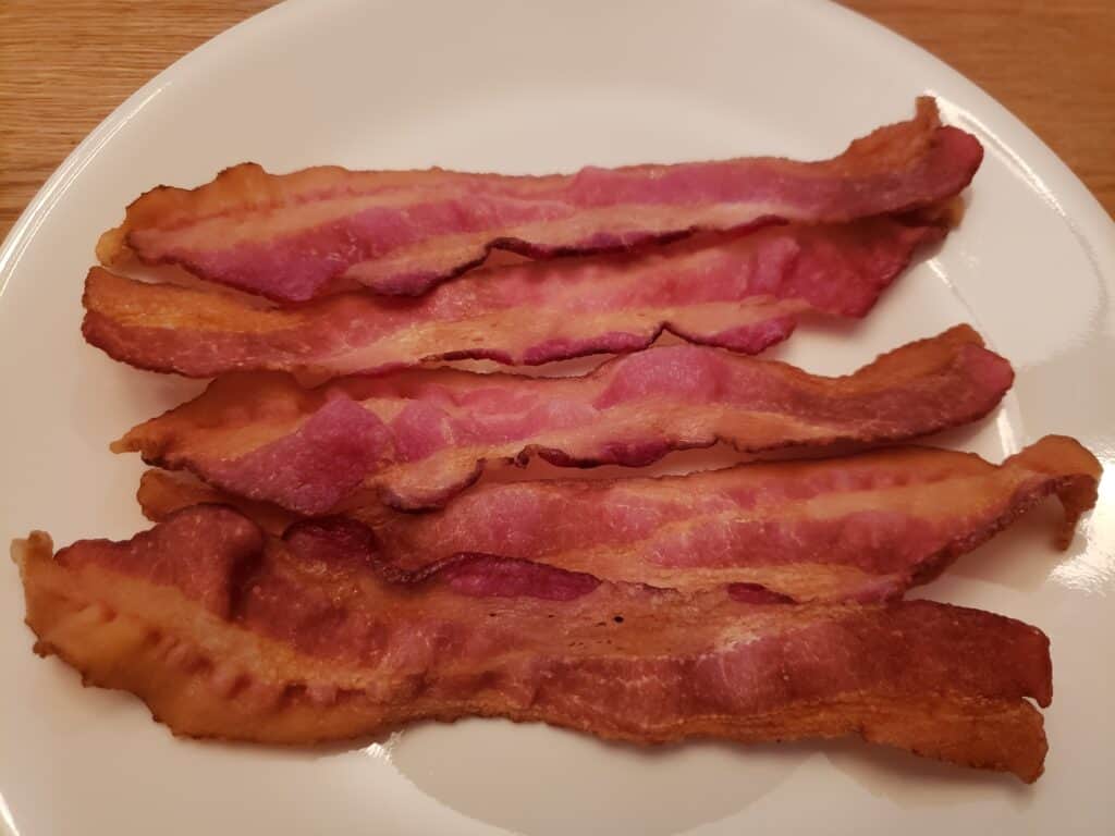 5 cooked slices of bacon on white plate