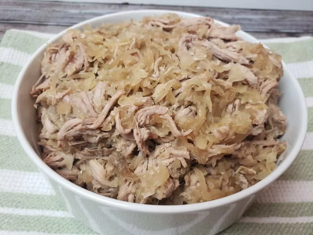 Crock Pot Pork and Sauerkraut in white serving bowl