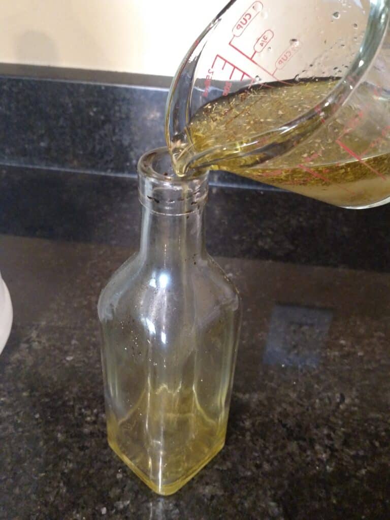 pouring homemade italian dressing into bottle