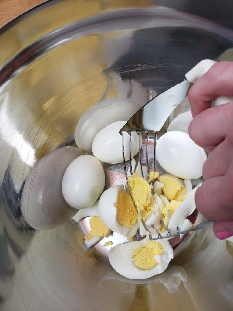 cutting hard boiled eggs in bowl with pastry cutter