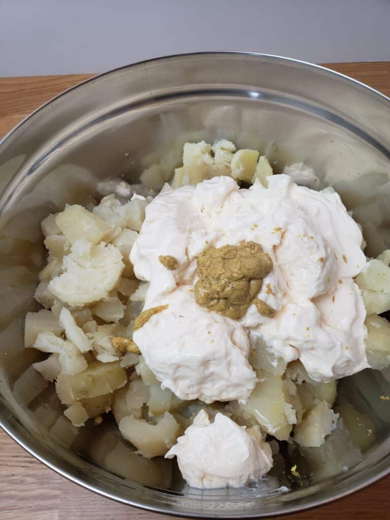 mayo, mustard and vinegar added to potatoes in bowl
