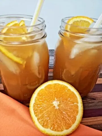Orange Honey Iced Tea in 2 mason jars with half an orange in front
