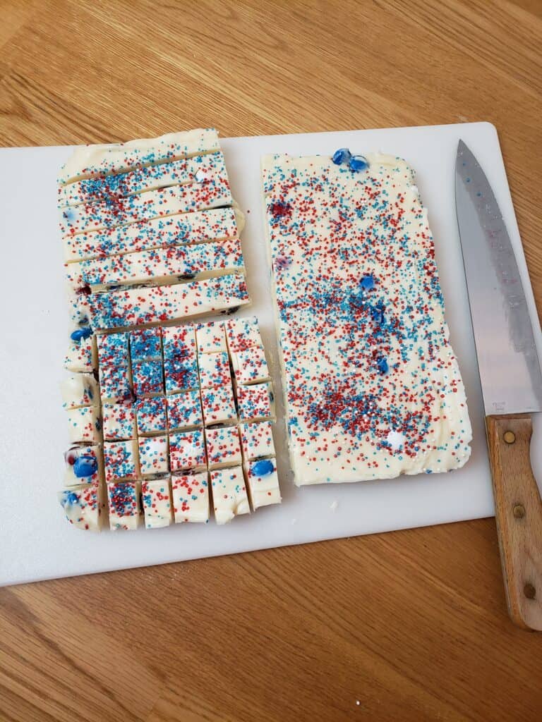 showing fudge on cutting board half uncut, quarter in strips and quarter is cut into bite sized pieces